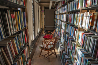 two wooden chairs in an aisle between shelves of books in Sterling Memorial Library